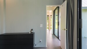 Et moderne soveværelse med en stor seng, en mørk trækommode og en skydedør til en balkon.