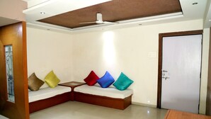 Quarto com sofá-cama de madeira, ventilador de teto e uma porta.