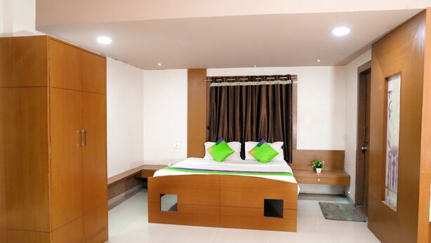 Quarto com estrutura de cama de madeira, mesa de cabeceira, guarda-roupa e cortina.