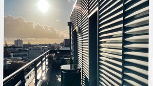 A balcony with a metal railing, a trash bin, and a wooden bench. - Cosy studio with panoramic terrace & parking (Tours)