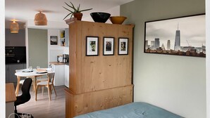 A bedroom with a bed, a wooden wardrobe, a dining area with a table and chairs, a kitchen, and a cityscape view. - Cosy studio with panoramic terrace & parking (Tours)