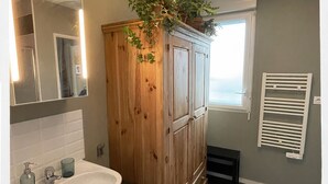 A bathroom with a wooden cabinet, a sink, and a mirror. - Cosy studio with panoramic terrace & parking (Tours)