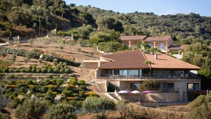 Une propriété située sur une colline, avec des maisons modernes, des jardins en terrasses et une vue dégagée sur le paysage environnant.
