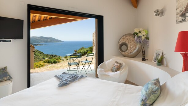 Une chambre avec un lit, une chaise, une petite table et une vue sur la mer.