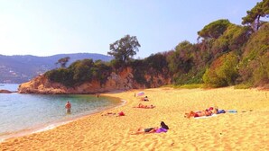 Une plage de sable où des gens se prélassent au soleil et se baignent.