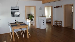 Een moderne woonruimte met een houten eettafel, witte stoelen en een houten kast.