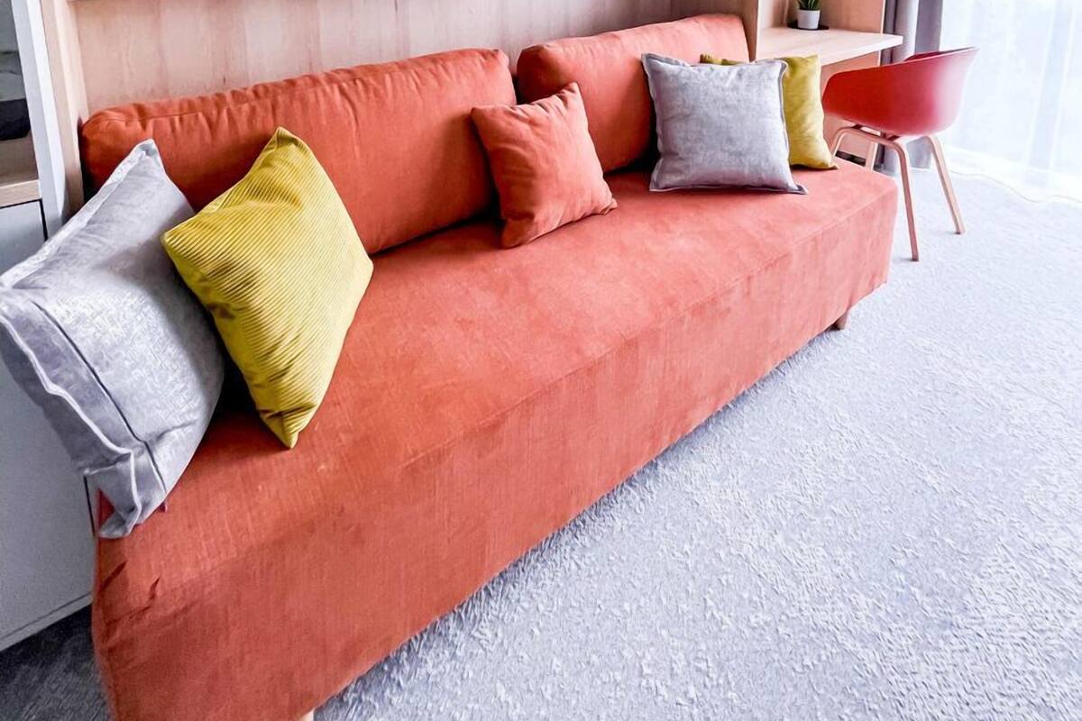 A modern living room with a sofa, cushions, a small table, and a potted plant.