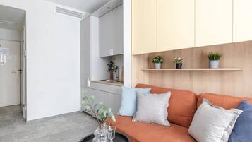 Uma sala de estar moderna com sofá, mesa de centro e área de cozinha ao fundo.