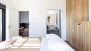 A modern hotel room with a bed, a wooden wardrobe, a bathroom with a sink and mirror, and a TV in the corner. - Villa Sea-Esta in Sellia with spectacular Sea view and pool, Adults Only (Rethymno)