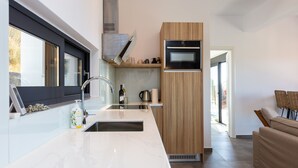 A modern kitchen with a built-in oven, a sink, and a window. - Villa Sea-Esta in Sellia with spectacular Sea view and pool, Adults Only (Rethymno)