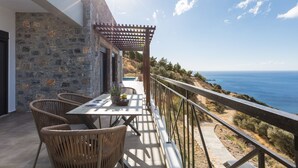 A balcony with wicker chairs, a table, and a pergola overlooking a coastal landscape. - Villa Sea-Esta in Sellia with spectacular Sea view and pool, Adults Only (Rethymno)