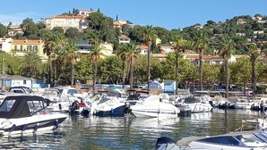 A marina with multiple boats docked, a clear blue sky, and buildings in the background.