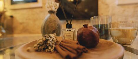 A wooden table with a plate containing cinnamon sticks, a pomegranate, and a bottle of perfume.