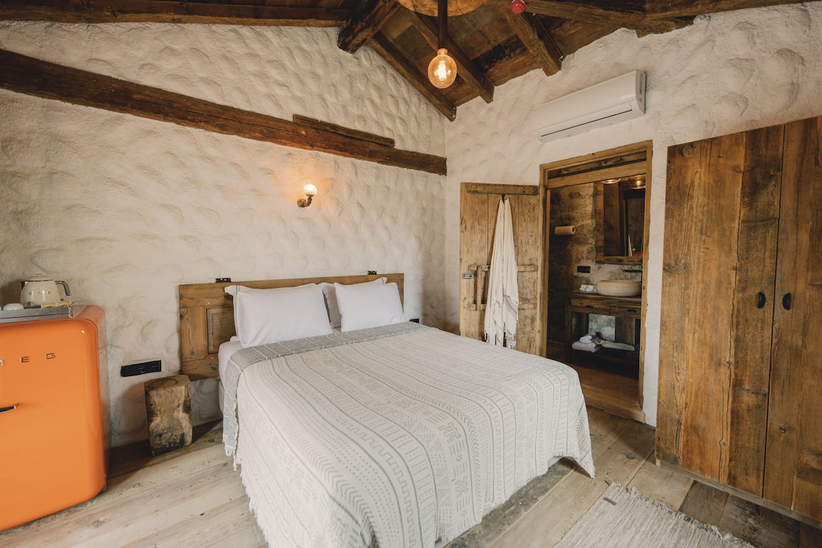 A bedroom with a bed, wooden wardrobe, and a vintage orange appliance.