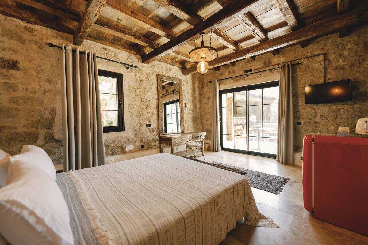 A rustic bedroom with a large bed, a desk, and a TV.
