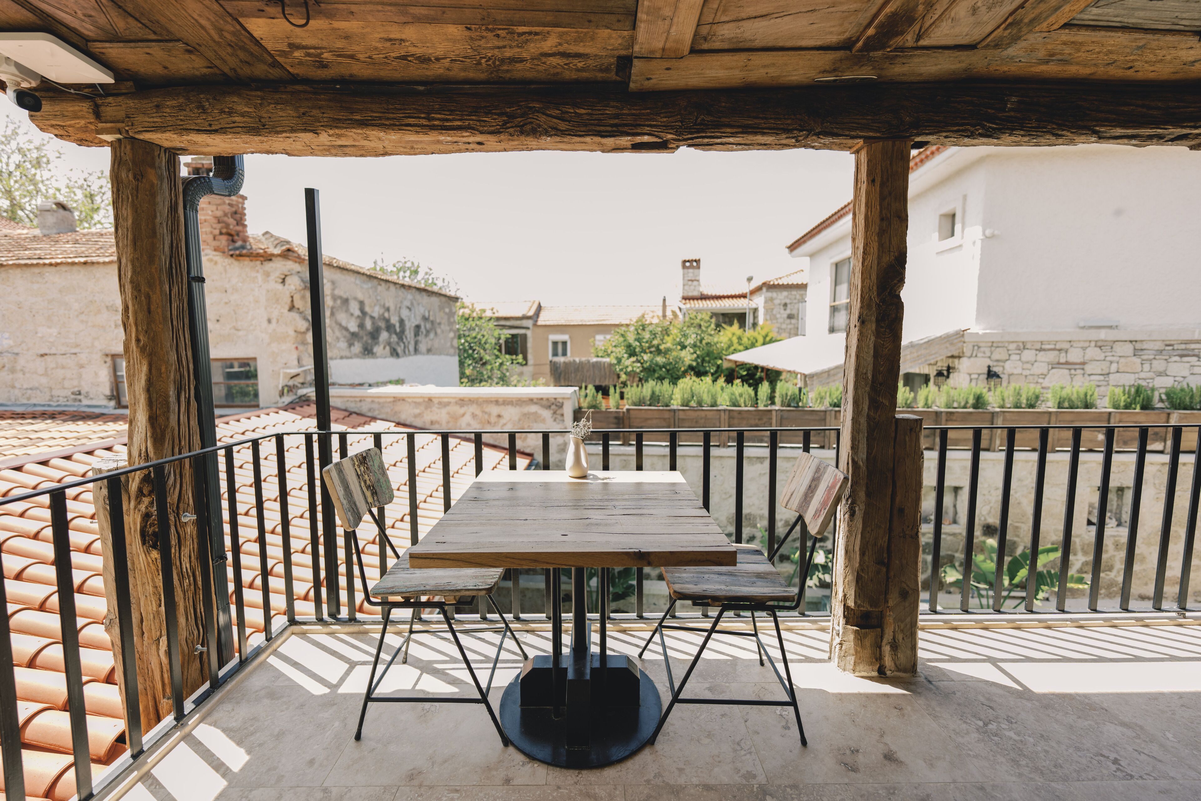 Ein Holztisch und -stühle unter einer Pergola mit Blick auf Gebäude und Grünflächen.