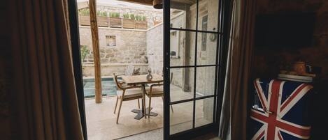 A room with a large sliding glass door leading to an outdoor area with a pool and a wooden table.
