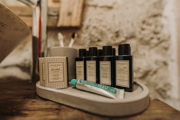 Un plateau contenant divers articles de toilette, notamment un tube de dentifrice, un savon et plusieurs flacons de gel douche.
