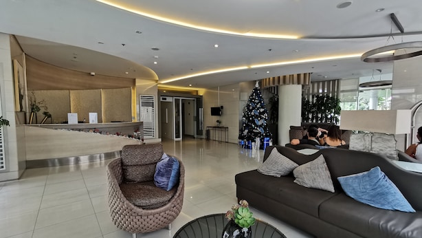 A modern lobby with a reception desk, seating area, and a Christmas tree. - 1BR Studio w/ Pool, Balcony, Near Airport&Hotspots (Taguig)