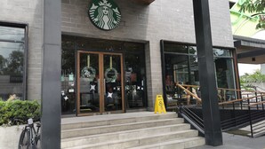A Starbucks with a modern brick facade, large glass windows, and a staircase leading to the entrance. - 1BR Studio w/ Pool, Balcony, Near Airport&Hotspots (Taguig)