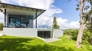 A modern house with a glass facade, a flat roof, and a well-maintained lawn. - Swimming pool along the terrace, panoramic view surrounded by nature  (หางดง)