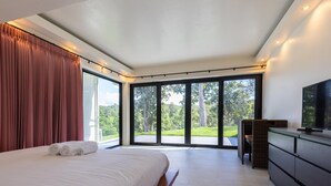 A modern bedroom with a large bed, a television, and a sliding glass door leading to a balcony. - Swimming pool along the terrace, panoramic view surrounded by nature  (หางดง)