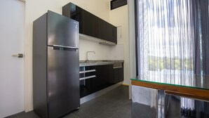 A modern kitchen with a stainless steel refrigerator, black cabinets, and a glass-top table. - Swimming pool along the terrace, panoramic view surrounded by nature  (หางดง)