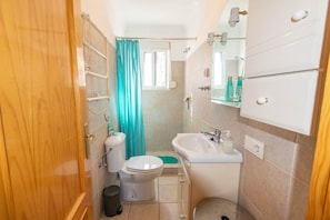A compact bathroom with a toilet, sink, and shower.