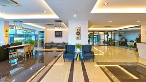 A modern hotel lobby with a reception desk, seating area, and glass doors leading to other rooms. - NORN Rimklong Bangkok Hotel (Bangkok)