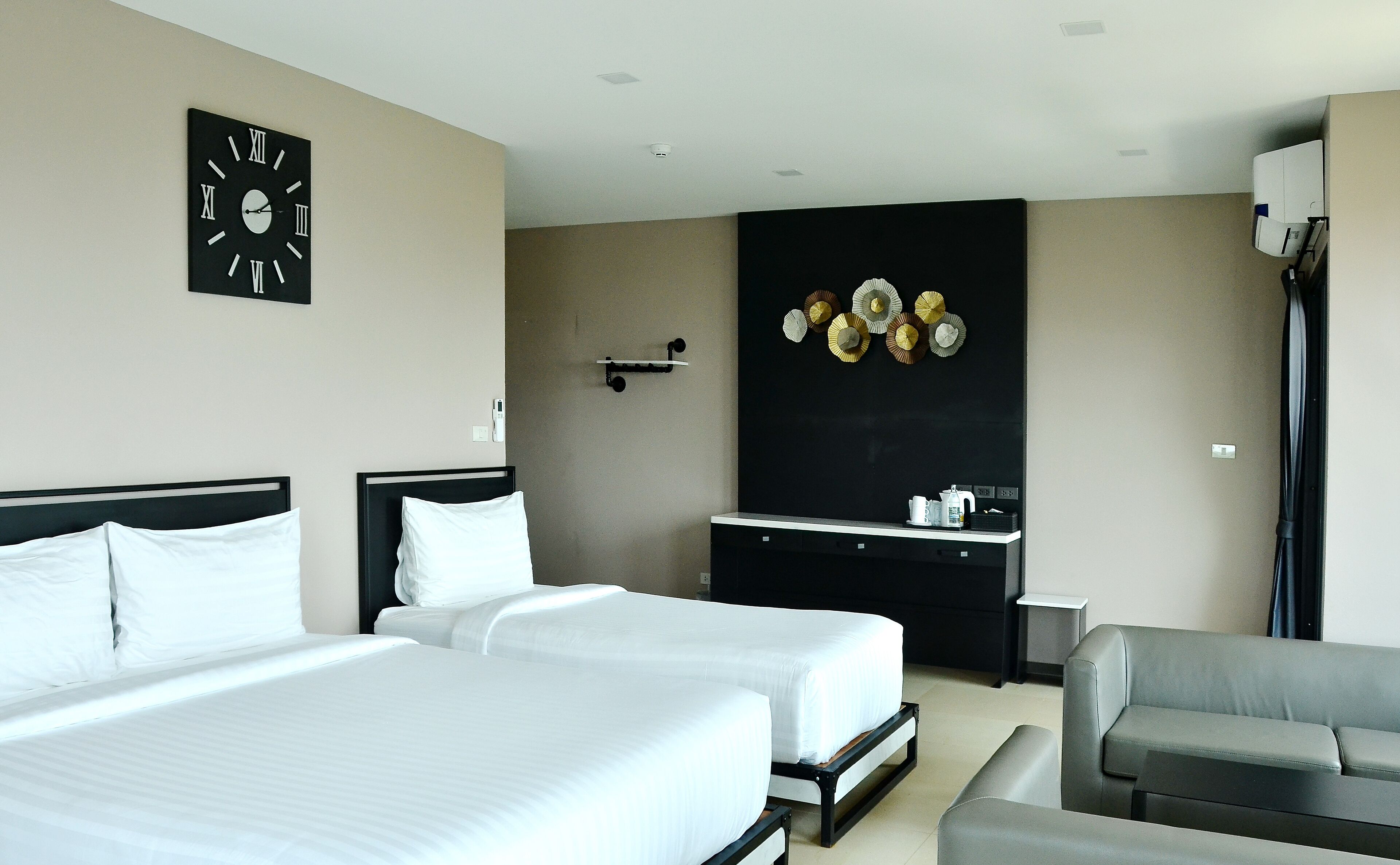 Habitación de hotel con dos camas, un escritorio, una silla, un reloj y un adorno en la pared.