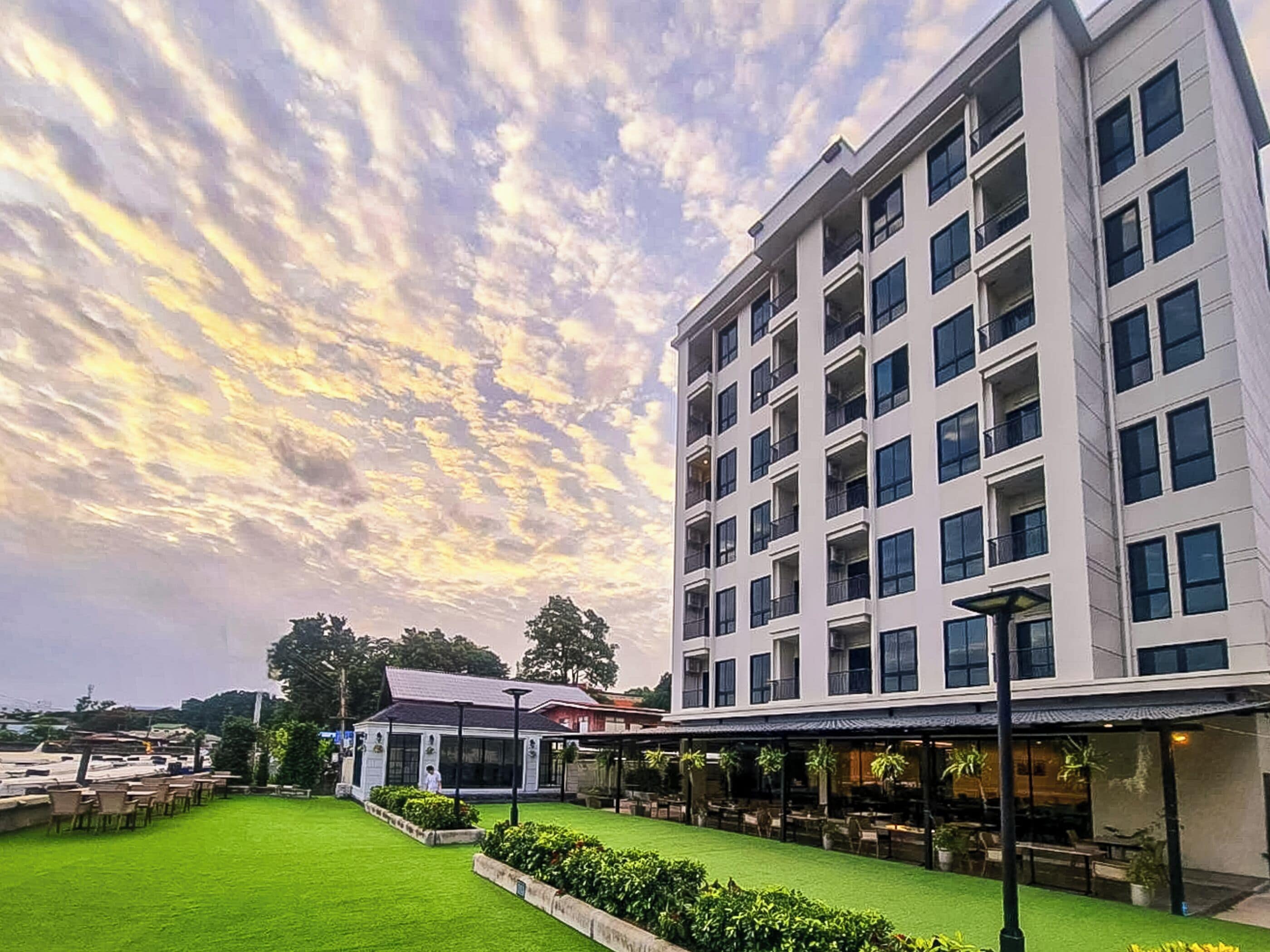 A modern hotel with a rooftop bar, a well-maintained lawn, and a large building with multiple balconies.