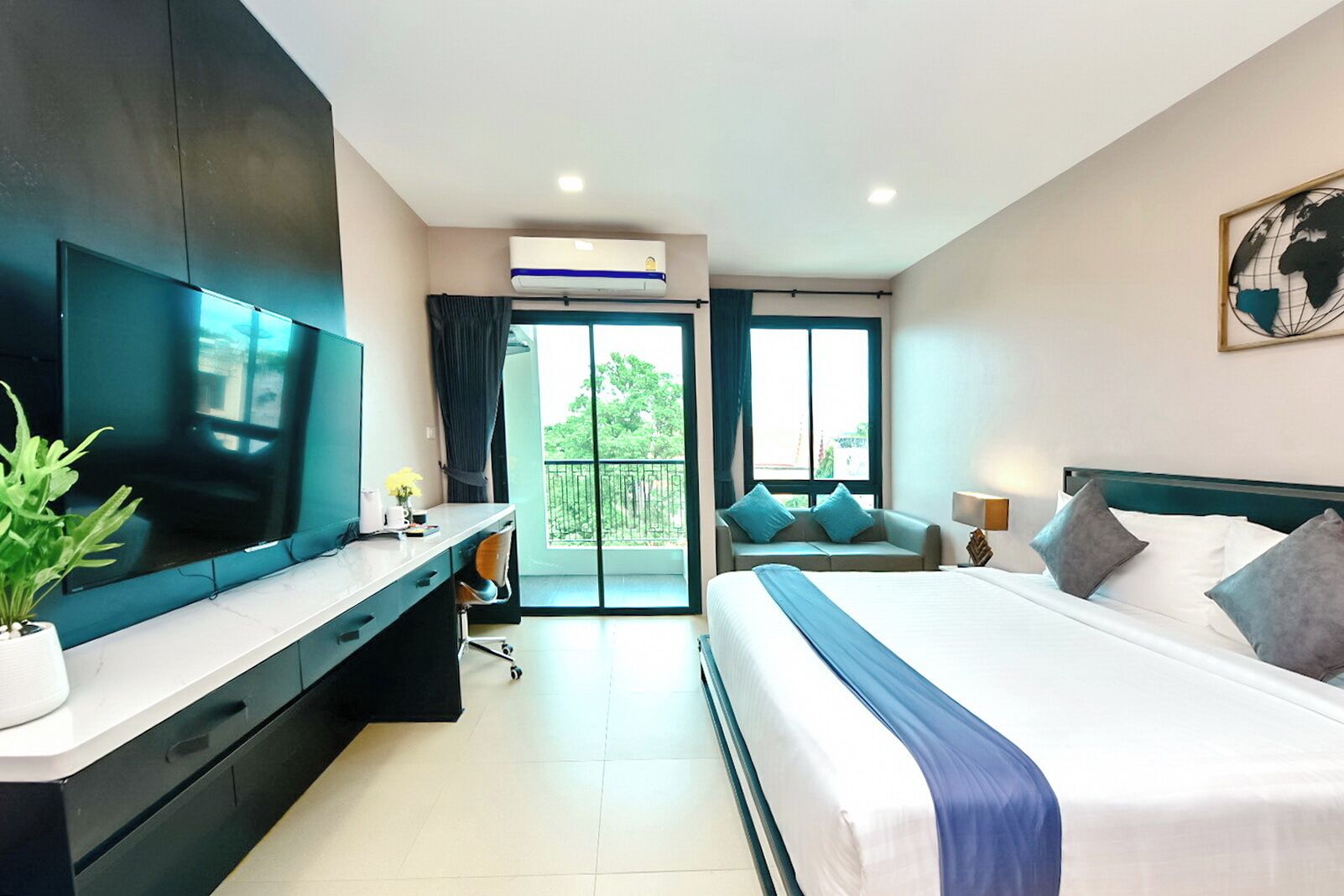 A modern hotel room with a large bed, a TV, a desk, and a balcony with a view.