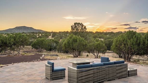 A patio with wicker furniture and a view of a hilly landscape at sunset. - Private home on 40 acres surrounded by wide open space. (Vernon)