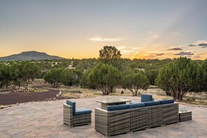 A patio with wicker furniture and a view of a hilly landscape at sunset. - Private home on 40 acres surrounded by wide open space. (Vernon)
