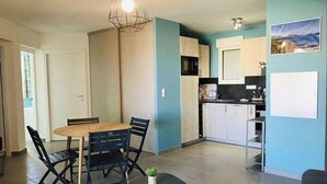 Une cuisine moderne avec des meubles blancs, un plan de travail noir et un luminaire suspendu.