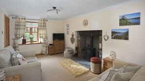 A cozy living room with a fireplace, comfortable seating, and a television. - Ivy Cottage, Balnaguard Detached cottage with off street parking. (Balnaguard)