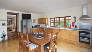 A modern kitchen with wooden cabinets, a stainless steel refrigerator, a gas stove, and a large window. - Ivy Cottage, Balnaguard Detached cottage with off street parking. (Balnaguard)