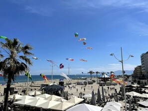 A beach with multiple tents and umbrellas, palm trees, and a clear blue sky. - Le Méditerranée - 1st Row, Ocean View, 3* Class (1st Row, Ocean View) (Canet-en-Roussillon)