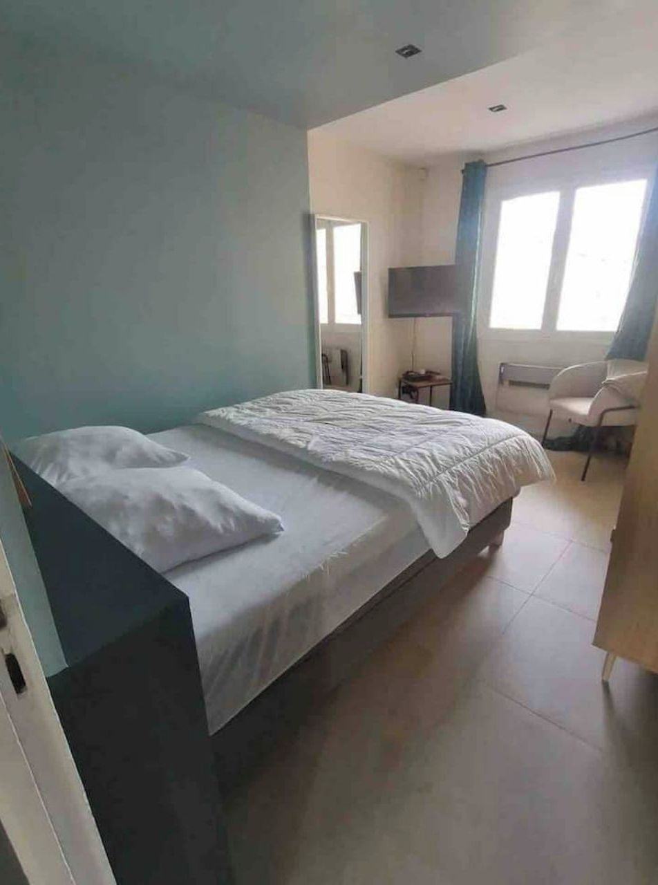 A single-bed room with a flat-screen TV, a desk, and a chair.