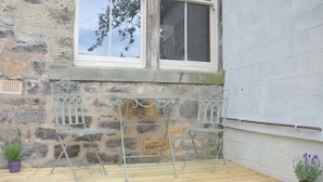 A stone wall with a window, two metal chairs, and a small table. - Coquetdale Cottage in Rothbury, quiet village location (Rothbury)