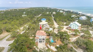 Et kystnært boligområde med huse omgivet af frodig vegetation og en strand i baggrunden.