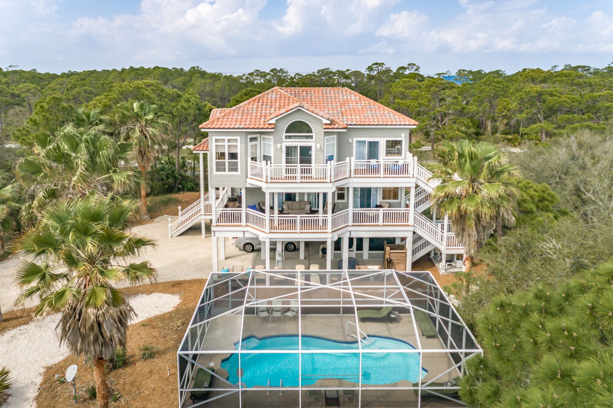 A two-story house with a red-tiled roof, multiple balconies, and a swimming pool.