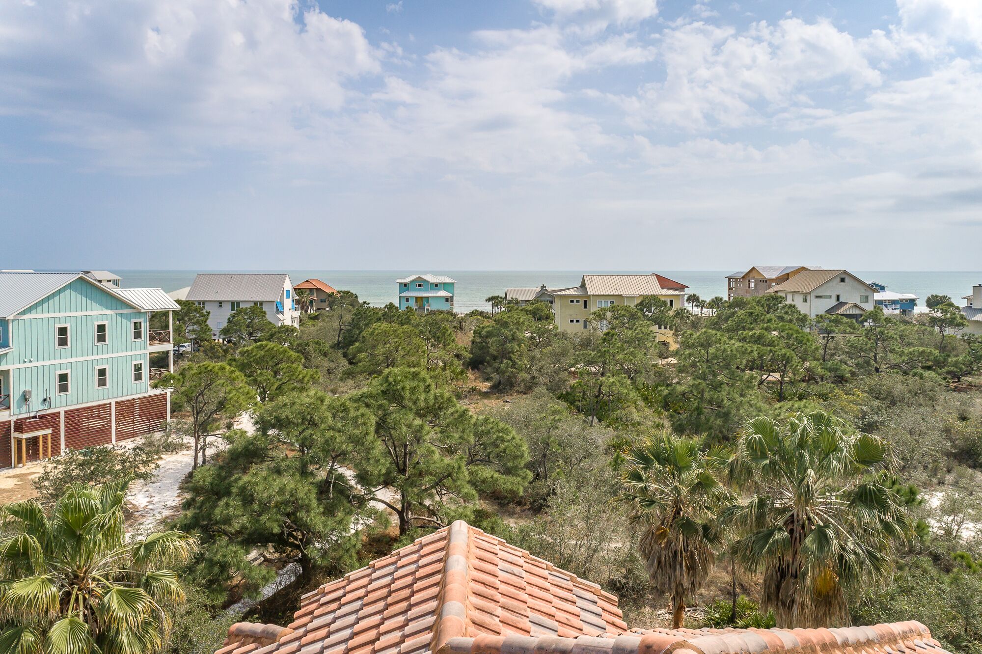 A coastal residential area with houses, a beach, and a clear sky.