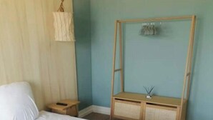 Une chambre à coucher avec un grand lit, une table de chevet en bois, une lampe suspendue et une commode en bois avec un miroir.