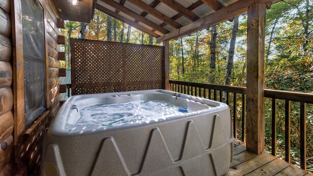 A hot tub on a wooden deck with a view of trees.