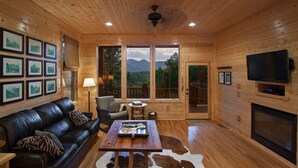 A cozy cabin interior with a leather couch, a wooden coffee table, and a fireplace.