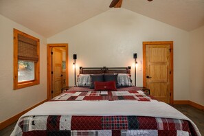 Ein Schlafzimmer mit einem großen Bett, zwei Nachttischlampen und einem Fenster mit Jalousien.