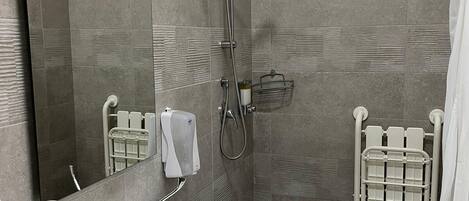 Un baño moderno con un lavamanos blanco, un cabezal de ducha de mano, un perchero y un espejo.