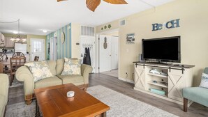 Un salon comprenant un canapé, une table basse, un meuble pour la télévision, ainsi qu’un coin repas avec des chaises et une table.