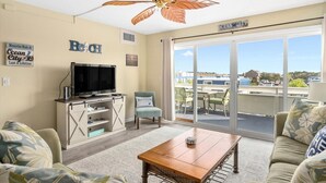 Un salon avec un téléviseur, une table basse et un canapé. Il y a une affiche sur le mur où l’on peut lire « Ocean City ».